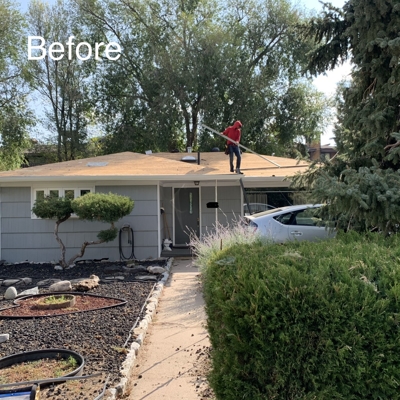 A person in a red shirt stands on the roof of a single-story house, cleaning or working. The word “Before” is displayed in the upper left. Trees and shrubs surround the house and a white car is parked in the driveway.